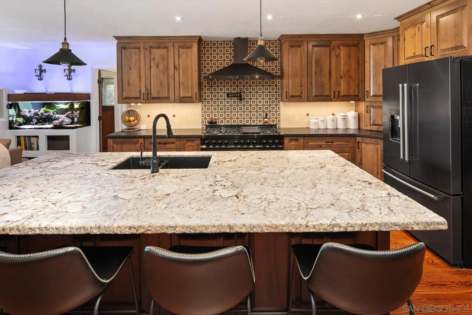 4195 Rochester Road San Diego, CA 92116 - Photo 21 of 39 a kitchen with kitchen island granite countertop a table chairs stove and refrigerator