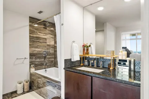 a bathroom with a granite countertop sink mirror bathtub and toilet