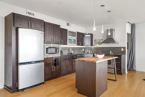 a kitchen with kitchen island a counter top space a sink stainless steel appliances and cabinets