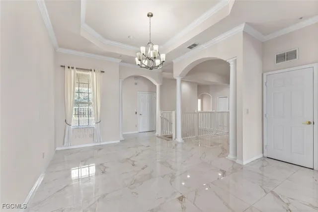 an empty room with chandelier and windows