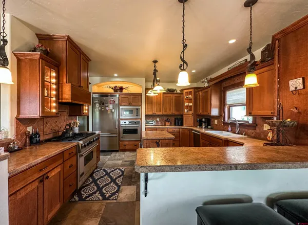 a kitchen with stainless steel appliances granite countertop a sink a stove and a wooden floors