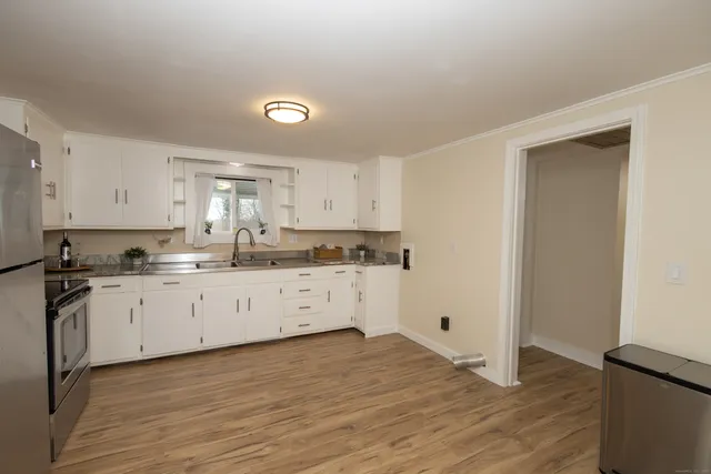 a kitchen with granite countertop white cabinets and wooden floor