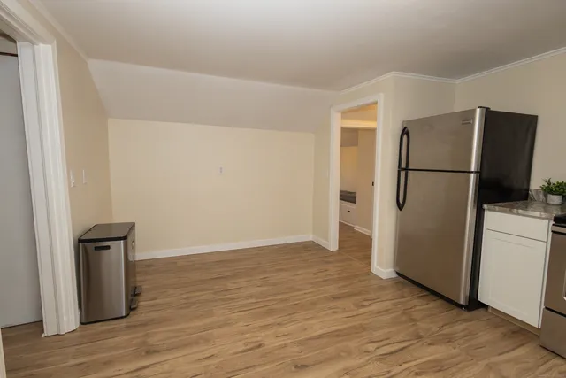 a view of a refrigerator in kitchen and an empty room