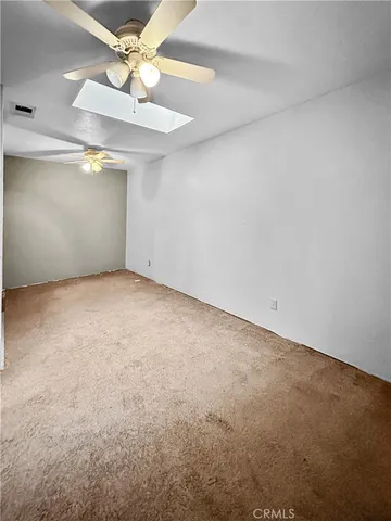 an empty room with a fan & a ceiling fan