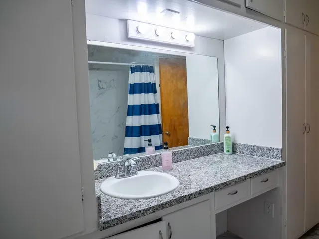 a bathroom with a granite countertop sink and a mirror