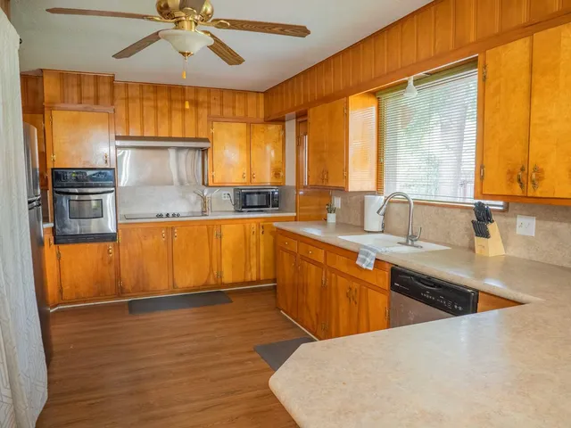 a large kitchen with stainless steel appliances a large window a sink and a counter space