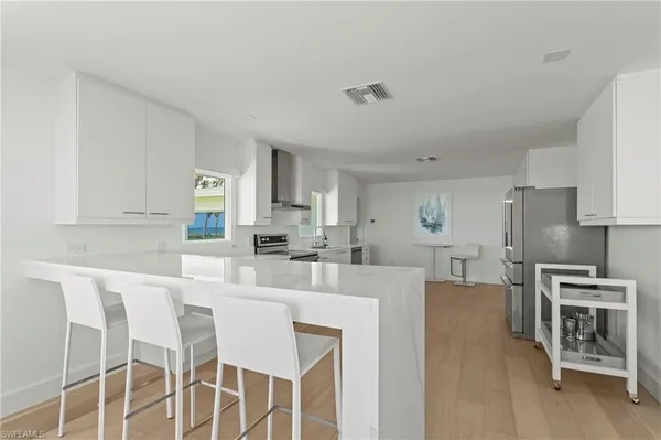 a kitchen with stainless steel appliances kitchen island granite countertop a table chairs and a refrigerator