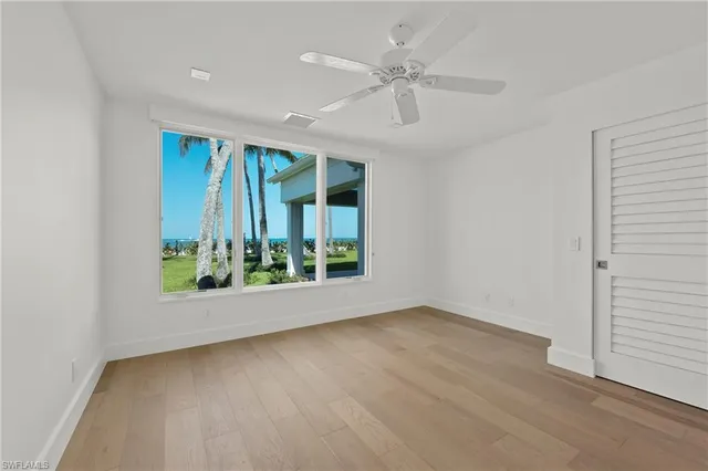 an empty room with wooden floor fan and windows