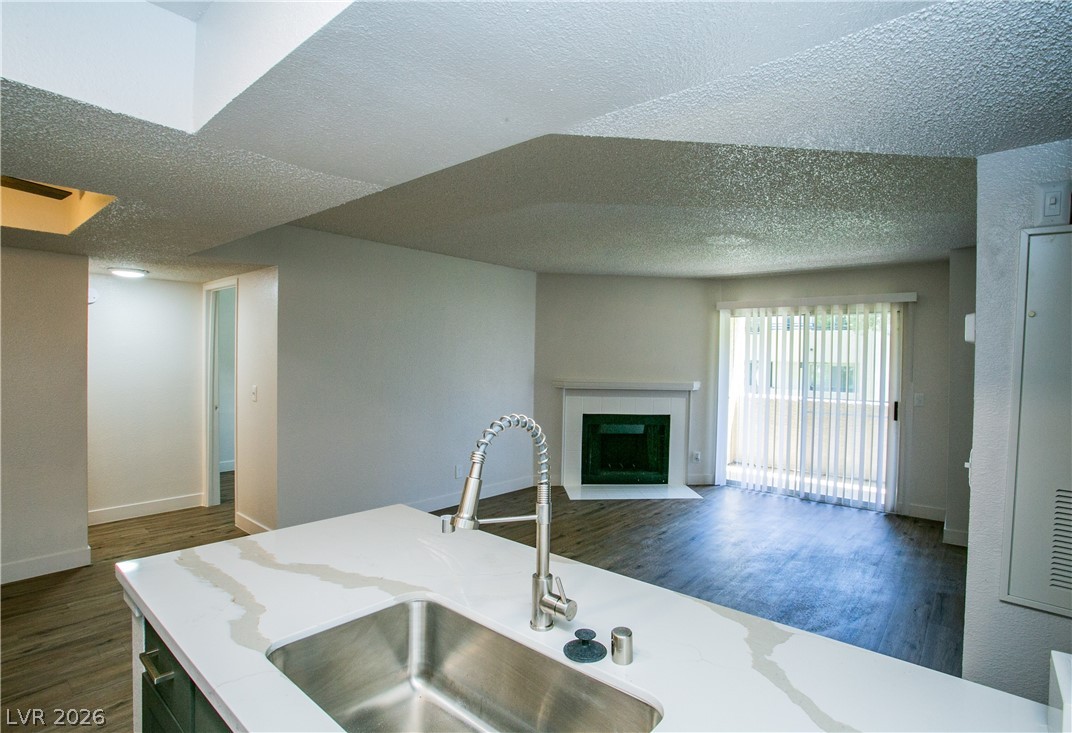 6750 Del Rey Avenue, Unit 108 Las Vegas, NV 89146 - Photo 3 of 11 This living space seamlessly connects to a kitchen island, featuring a sleek sink and a captivating fireplace.
