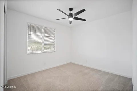 an empty room with ceiling fan and window