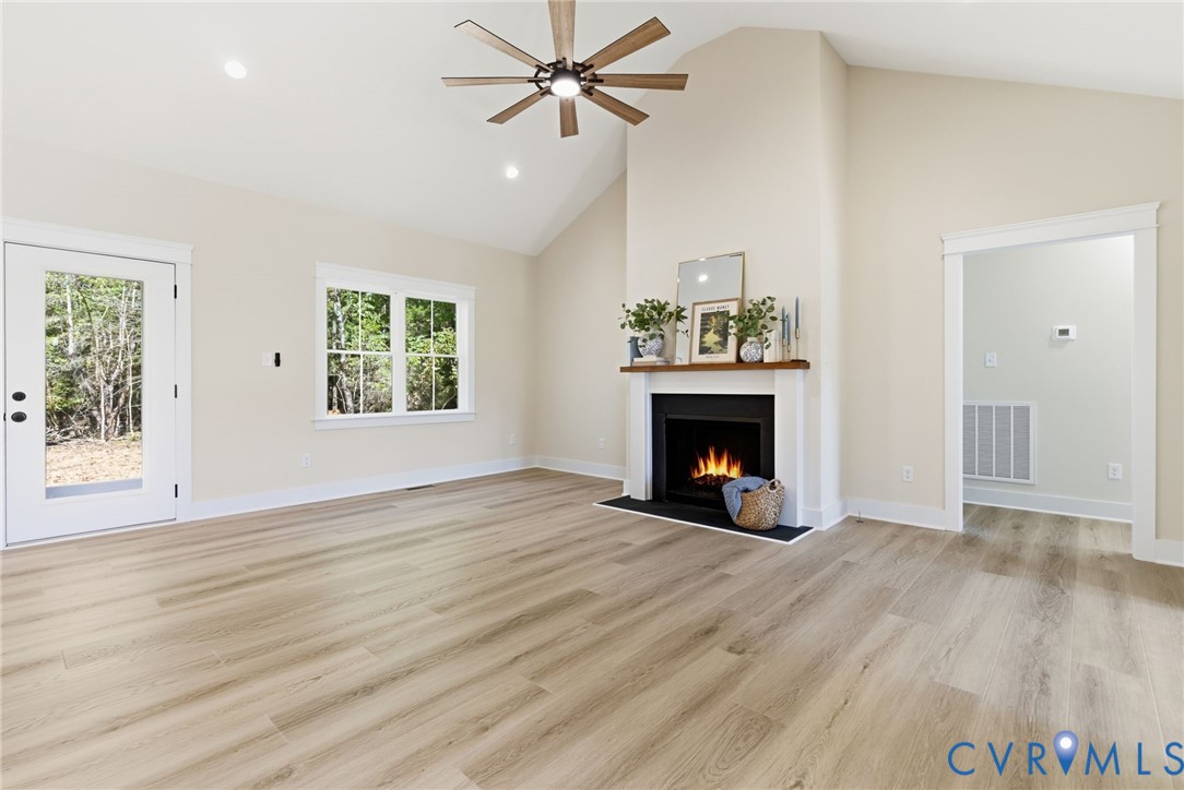 7376 River Road Hanover, VA 23069 - Photo 16 of 46 an empty room with windows a fireplace a ceiling fan and wooden floor