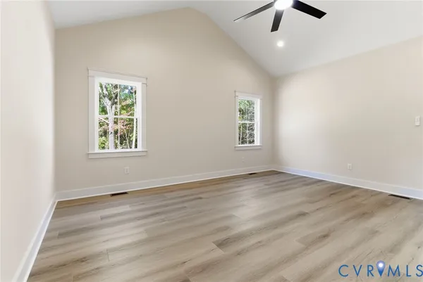 an empty room with wooden floor chandelier fan and windows