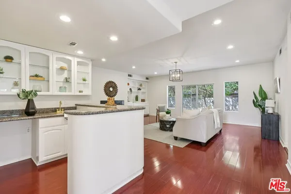 a living room with kitchen island granite countertop furniture a potted plant and a sink