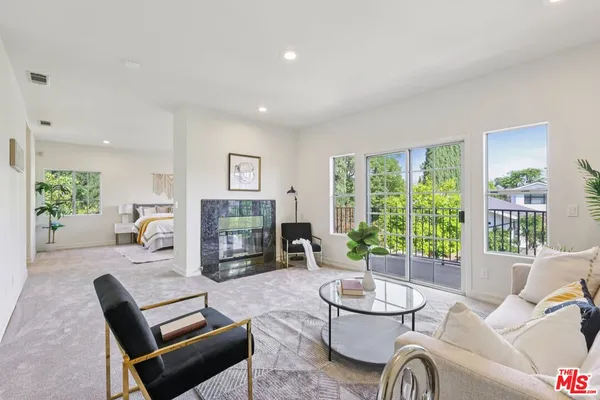 a living room with furniture a fireplace and a table with garden view