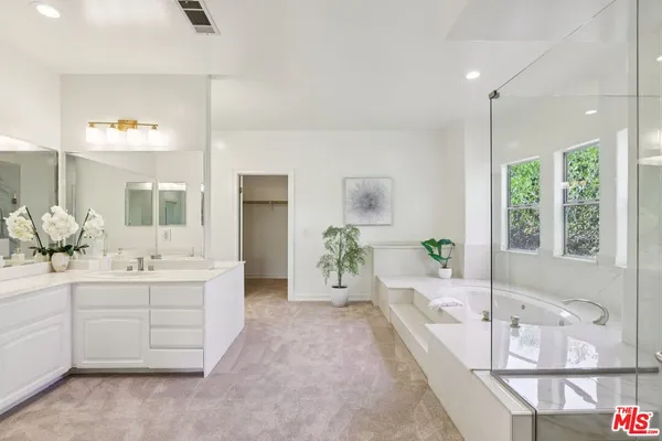 a large spacious bathroom with a double vanity sink a large mirror and a bathtub