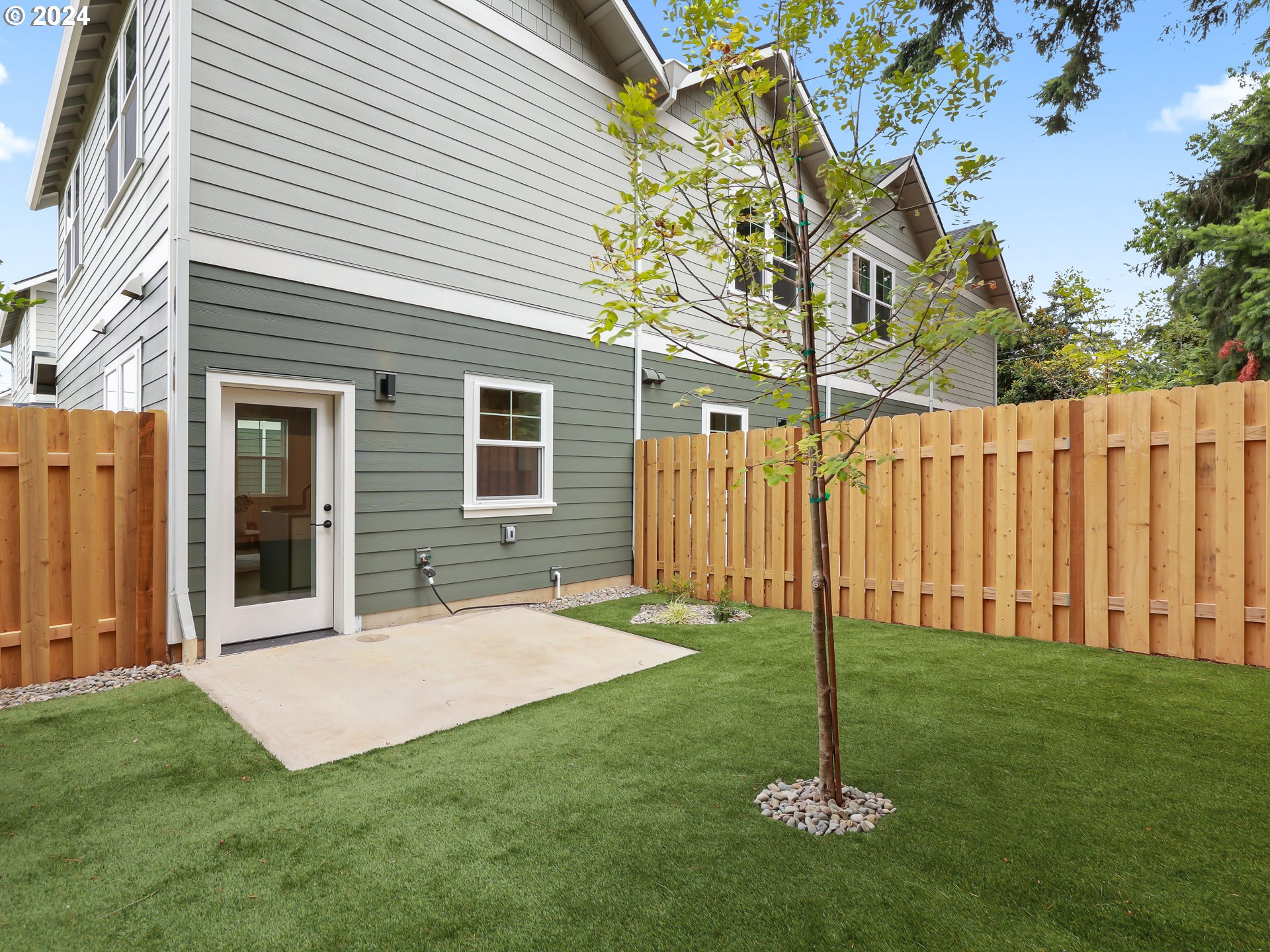 4636 Northeast Sumner Street Portland, OR 97218 - Photo 32 of 39 a backyard of a house with plants and wooden fence