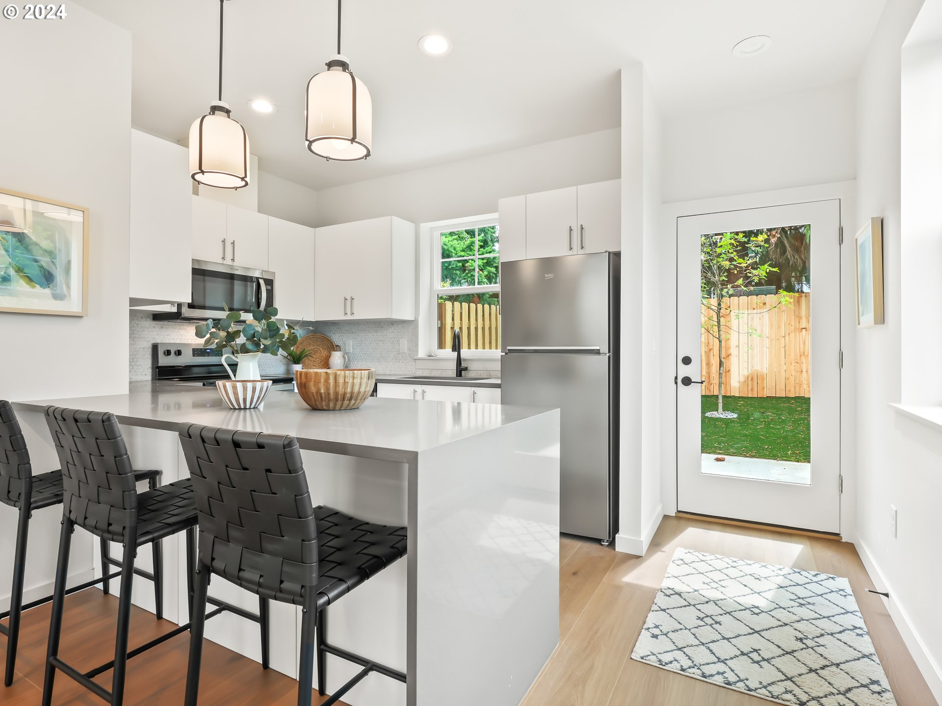 4636 Northeast Sumner Street Portland, OR 97218 - Photo 10 of 39 a kitchen with stainless steel appliances granite countertop a refrigerator a sink dishwasher a dining table and chairs with wooden floor