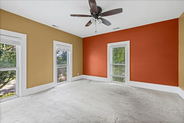 an empty room with windows and fan