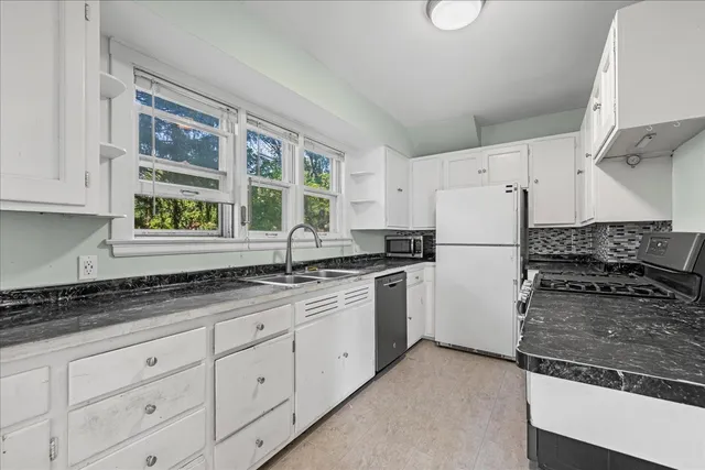 a kitchen with granite countertop a refrigerator sink and cabinets