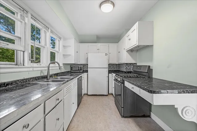 a kitchen with granite countertop a sink stove and refrigerator