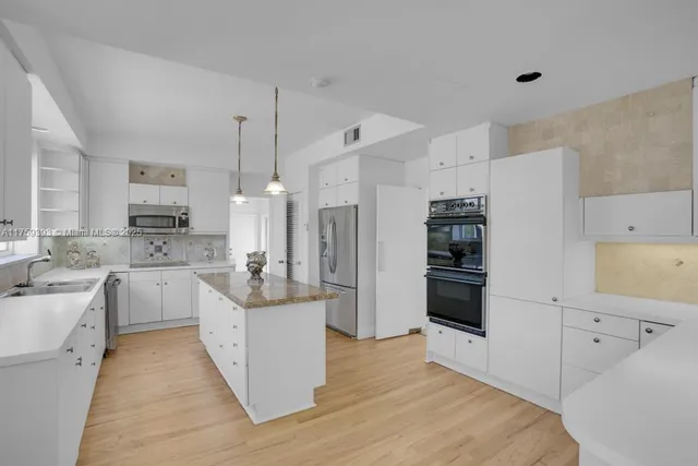a large white kitchen with cabinets and stainless steel appliances