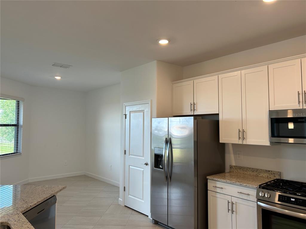 15513 White Linen Drive Lakewood Ranch, FL 34211 - Photo 14 of 35 a kitchen with stainless steel appliances granite countertop a refrigerator a stove and a sink with wooden floor