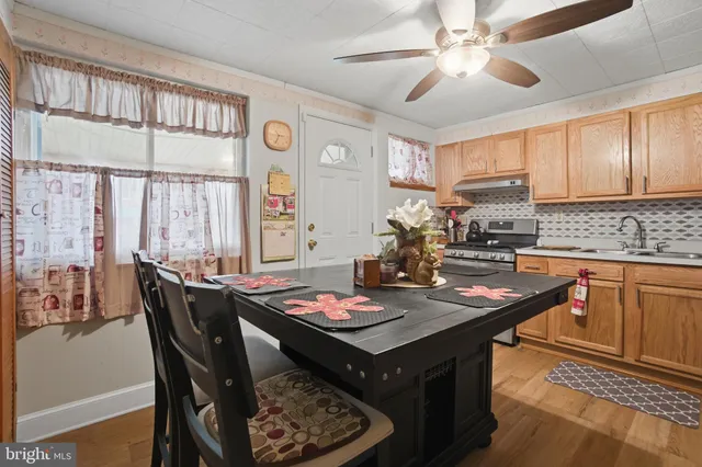 a kitchen with a stove a sink dishwasher a dining table and chairs with wooden floor