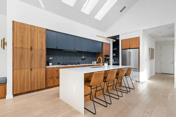 a kitchen with stainless steel appliances a dining table chairs and refrigerator