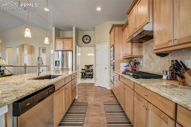 12442 Carmel Ridge Road Colorado Springs, CO 80921 - Photo 15 of 50 Kitchen featuring pendant lighting, sink, light stone counters, and appliances with stainless steel finishes