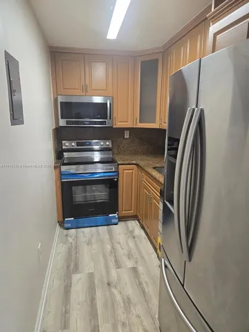a kitchen with granite countertop a refrigerator and a stove top oven
