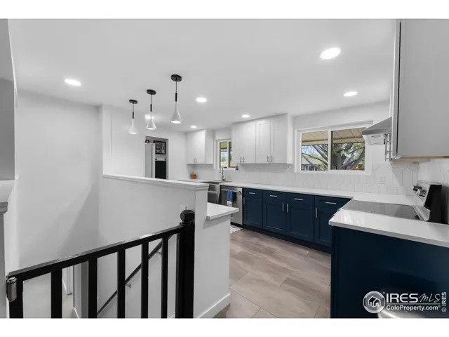 a large kitchen with stainless steel appliances kitchen island a large counter top a sink cabinets and a wooden floor