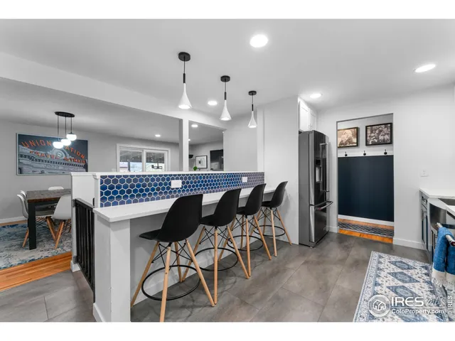 a kitchen with stainless steel appliances kitchen island granite countertop dining table chairs and a refrigerator