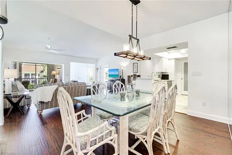 a view of a dining room and livingroom with furniture wooden floor a chandelier