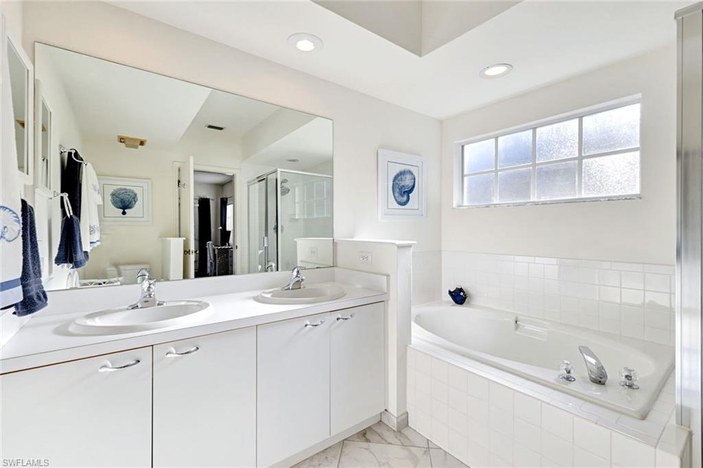 109 Tuscana Court, Unit 308 Naples, FL 34119 - Photo 10 of 18 a bathroom with a tub a sink and mirror