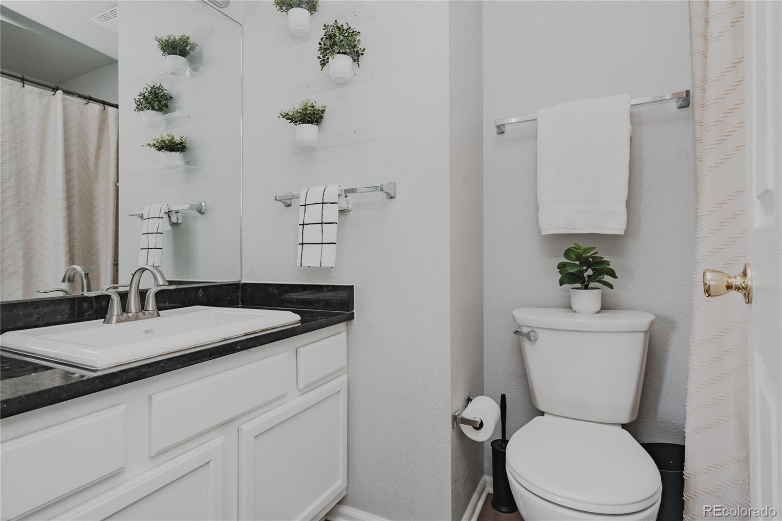 5081 Garrison Street, Unit 9 Wheat Ridge, CO 80033 - Photo 20 of 31 a bathroom with a granite countertop toilet sink and mirror
