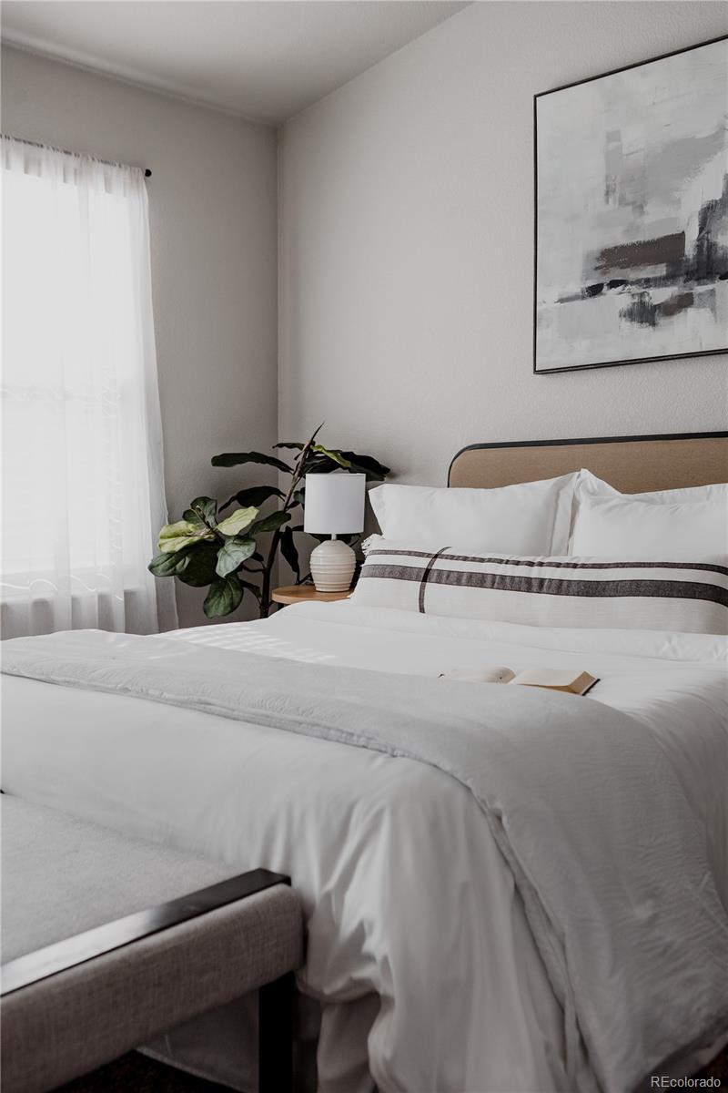 5081 Garrison Street, Unit 9 Wheat Ridge, CO 80033 - Photo 23 of 31 a bedroom with a bed and a painting on the wall