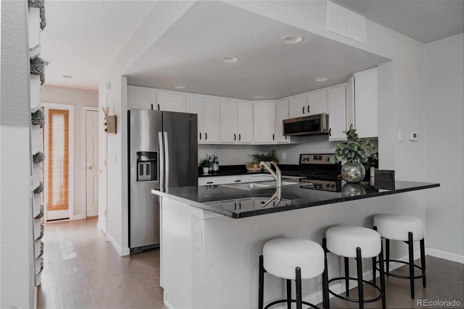 5081 Garrison Street, Unit 9 Wheat Ridge, CO 80033 - Photo 4 of 31 a kitchen with stainless steel appliances a refrigerator stove microwave and cabinets