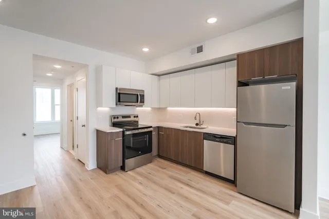 a kitchen with stainless steel appliances granite countertop a refrigerator a stove top oven a sink and dishwasher with wooden floor