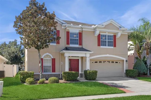 a view of a white house with a small yard and large tree