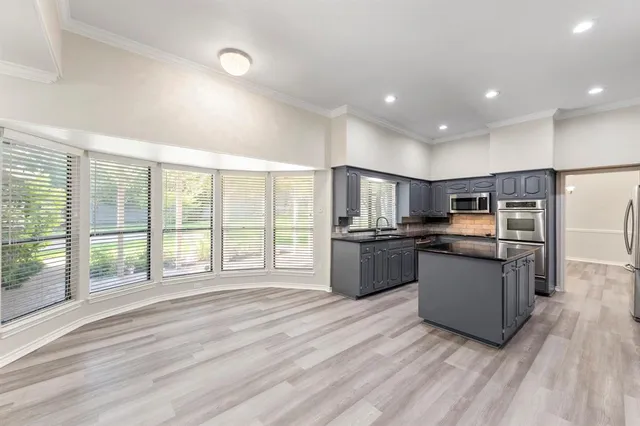 a large kitchen with stainless steel appliances granite countertop a large center island and a wooden floors