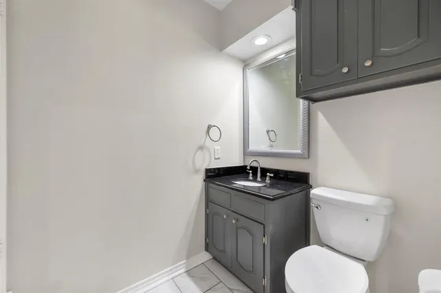 a bathroom with a granite countertop toilet sink and mirror