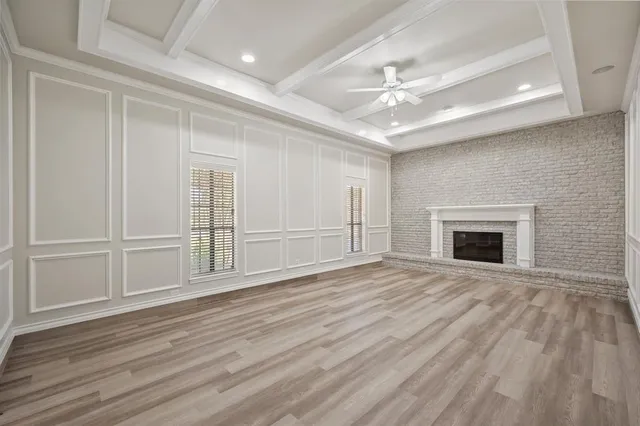 an empty room with wooden floor fireplace and windows