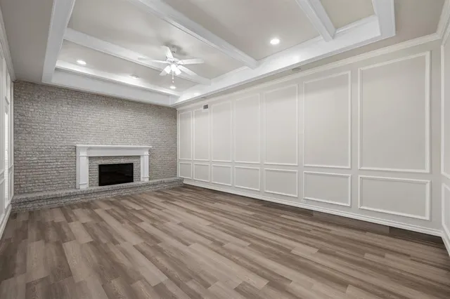 a view of an empty room with wooden floor fireplace and a window