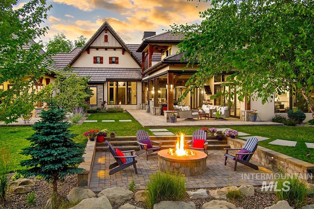 1582 East Rivers End Court Eagle, ID 83616 - Photo 6 of 49 Back of house at dusk with an outdoor living space with a fire pit, a patio area, a lawn, a tile roof, and stucco siding