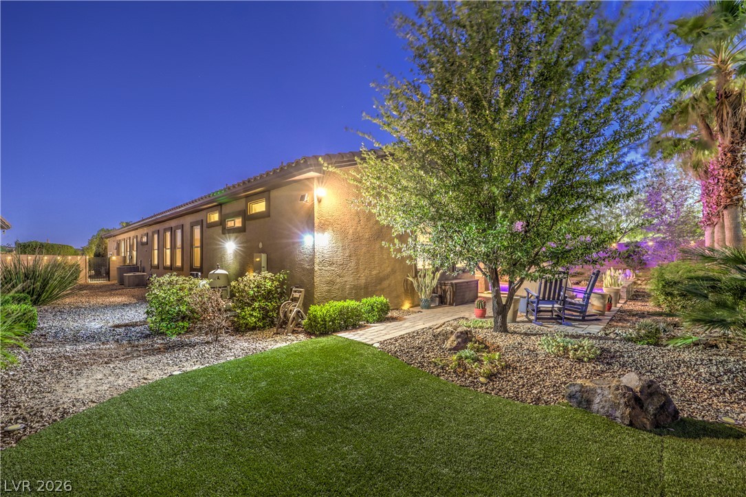 7119 Arabian Ridge Street Las Vegas, NV 89131 - Photo 55 of 73 Artfully illuminated backyard features a blend of gravel and artificial turf, offering a serene outdoor retreat.