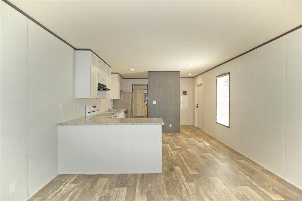60 Tecumseh Road Valley View, TX 76272 - Photo 8 of 20 Open-concept living space with wood-finish flooring, a kitchen island with a countertop, white cabinetry, integrated range hood, and a white oven