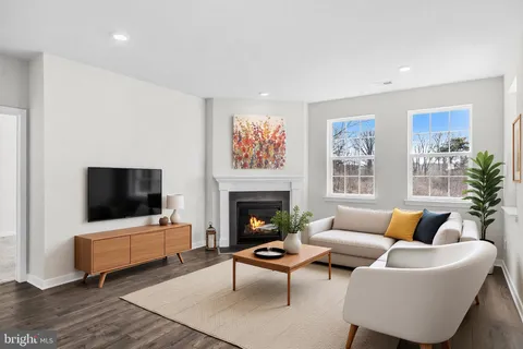 a view of an empty room with wooden floor fireplace and a window