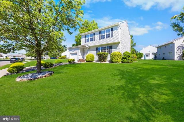 a view of a house with a big yard plants and large trees