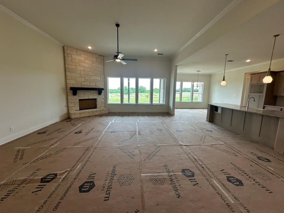205 Cobb Road Leonard, TX 75452 - Photo 9 of 28 Spacious living area featuring a stone-clad fireplace with a dark wood mantel, a ceiling fan, and multiple windows