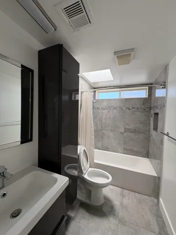 a bathroom with a bathtub shower sink vanity and toilet